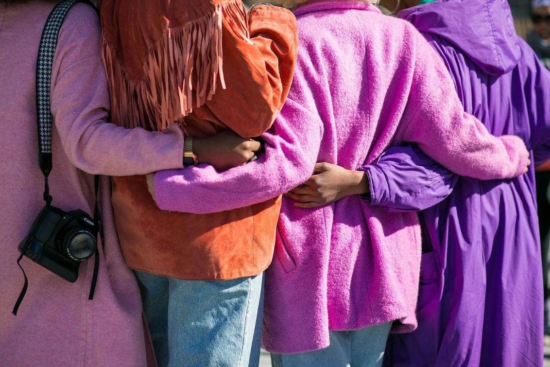 Four women standing together with hands around waist