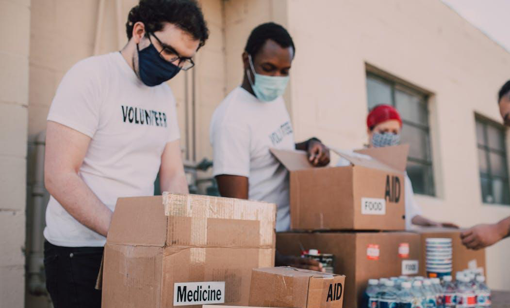 A group of volunteers sorting food, medicine, and other supplies in cardboard boxes